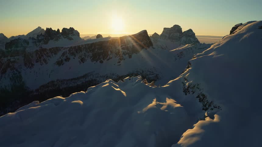 The sun shines on a snowcovered mountain range