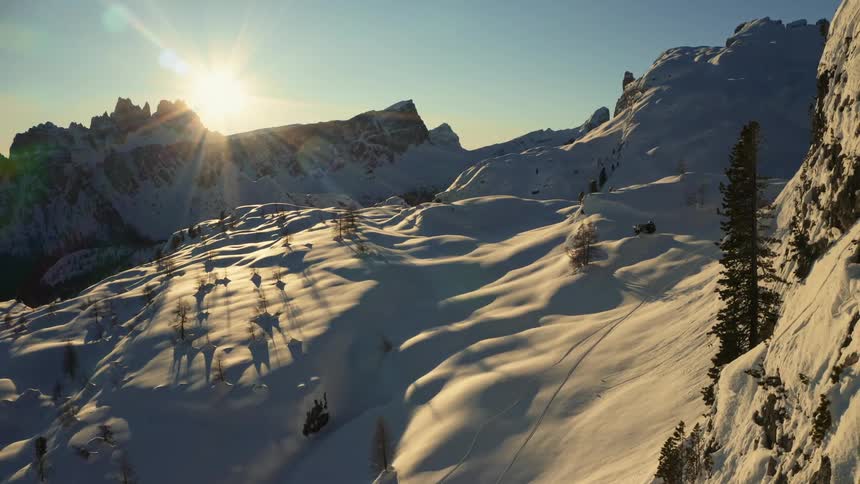 Bright sunlight shines onto a snow covered mountain