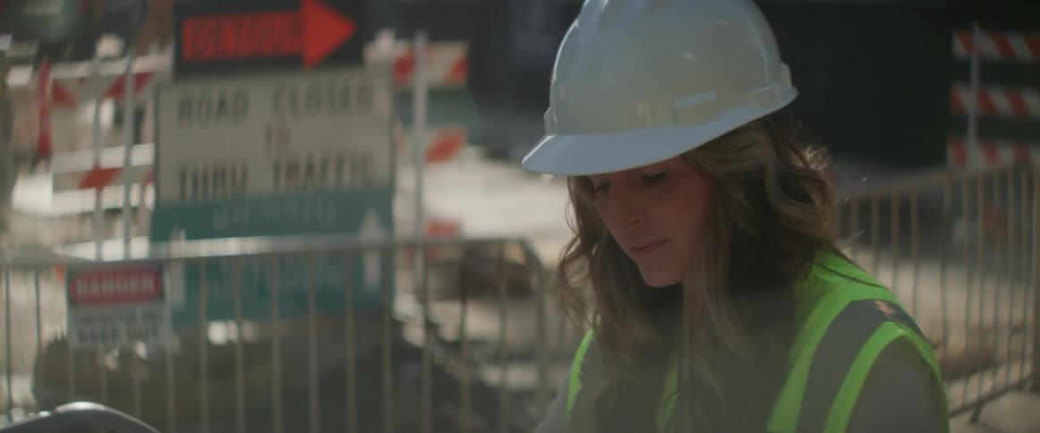 A woman looks at blueprints on a construction site