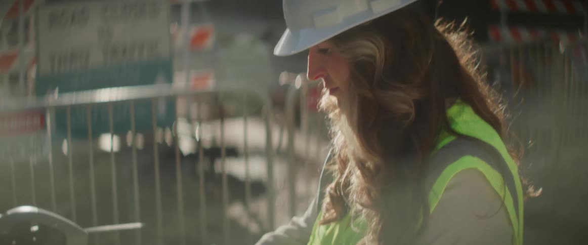 A female construction worker standing at a site using small machines