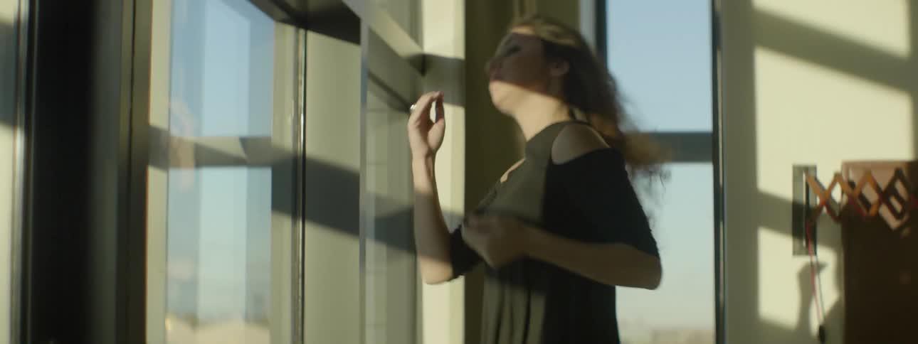 Woman walking to a window to look outdoors in the city