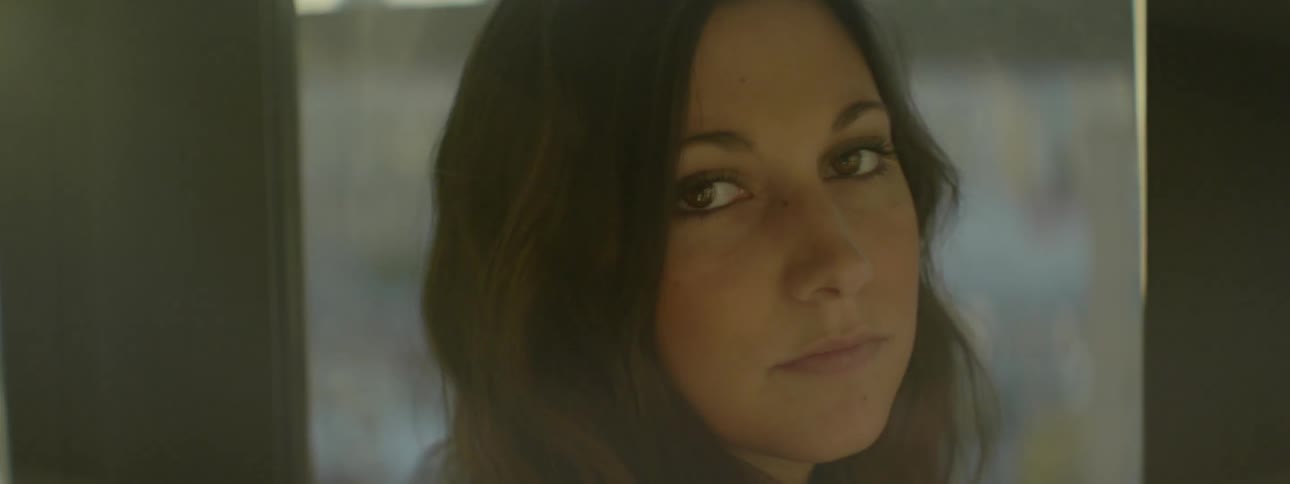 A woman turns from looking out the window