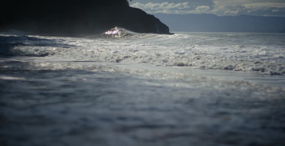 Ocean waves wash into a beach during the day