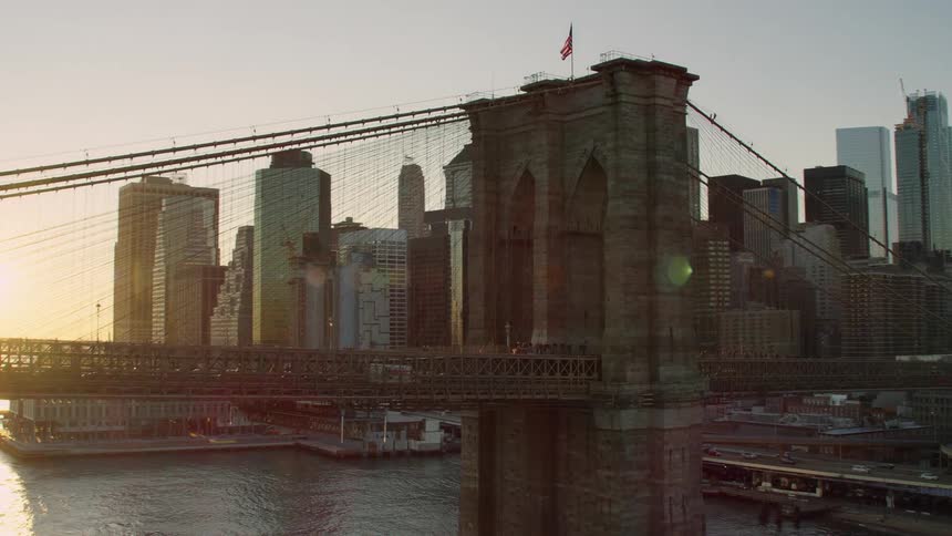 Aerial view of the brooklyn bridge in front of the new york city skyline at sunset
