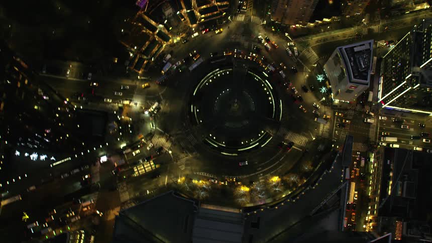 A city with a roundabout with vehicles surrounded by buildings and skyscrapers