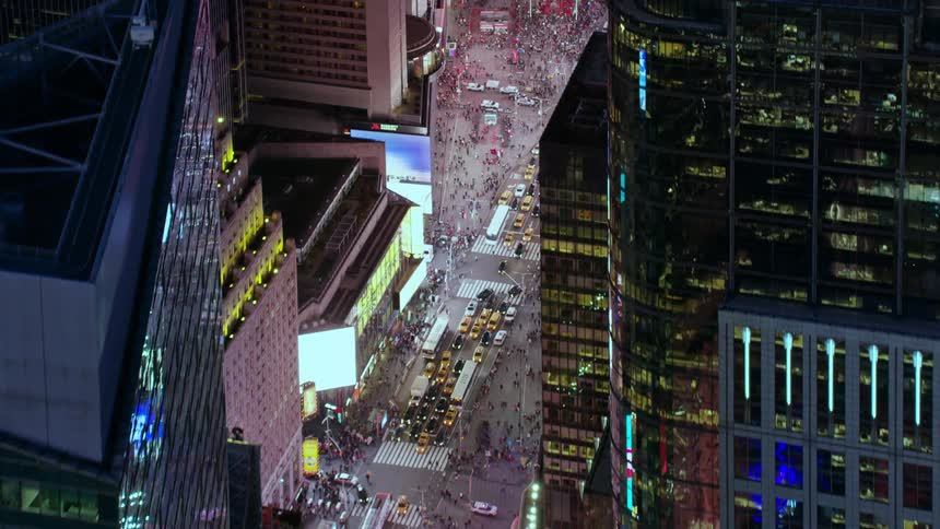 An aerial view of people and cars lining a busy city street with office buildings and stores