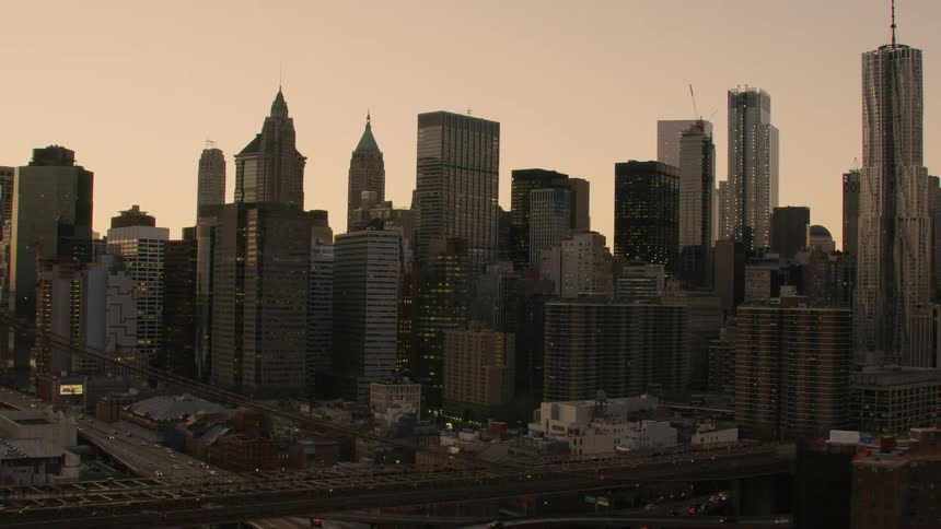 A city with a bridge over a river with buildings skyscrapers the sky and clouds in the background