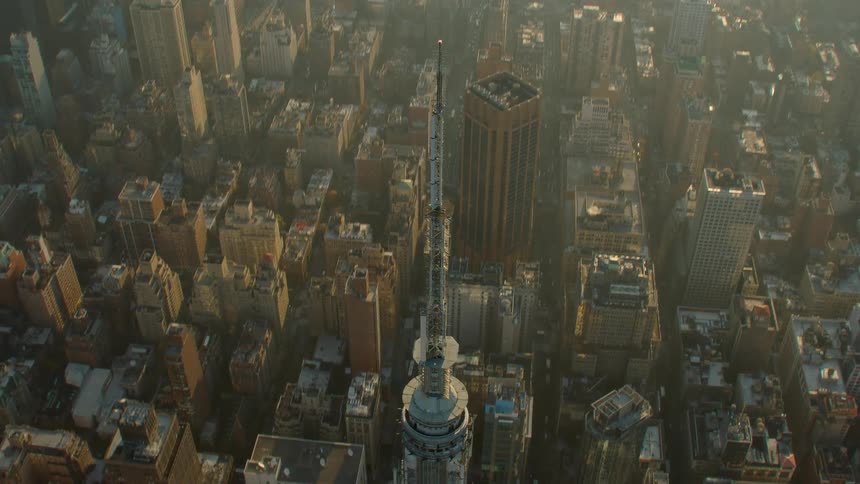 A skyscraper with a tall spire towers over surrounding buildings downtown