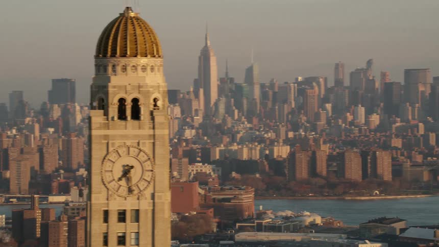 A clock tower rises high in the sky with a large city as a backdrop