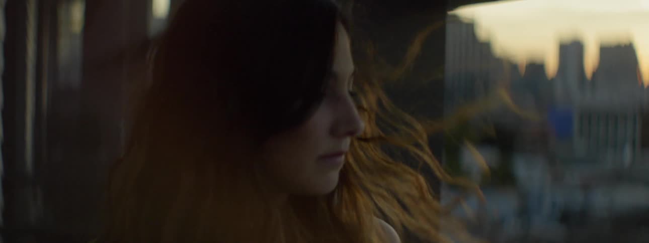 Breeze blows young woman's hair as she overlooks the city