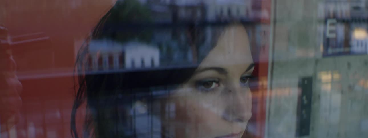 A woman is seen looking out a window inside