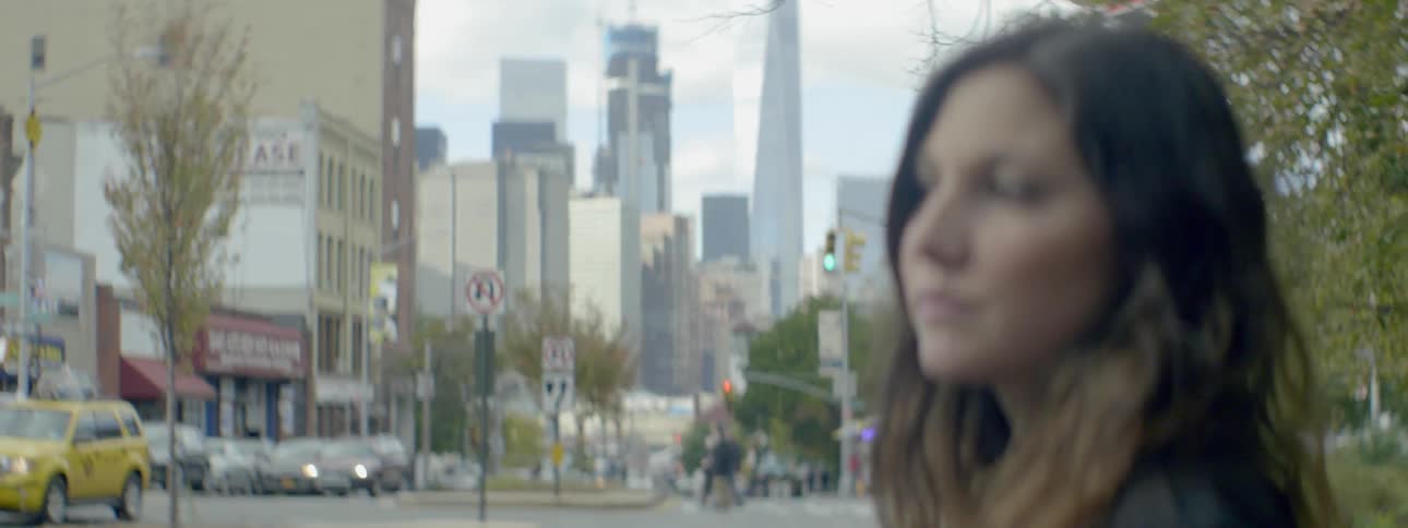 A woman is standing in the street looking around a city