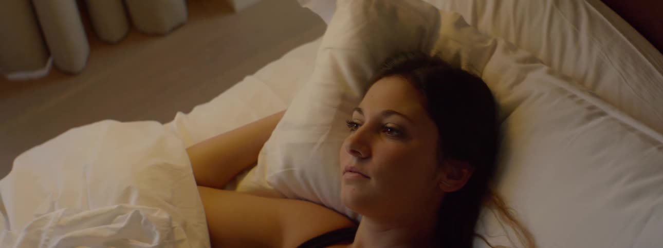 A woman lays down in the bed awake