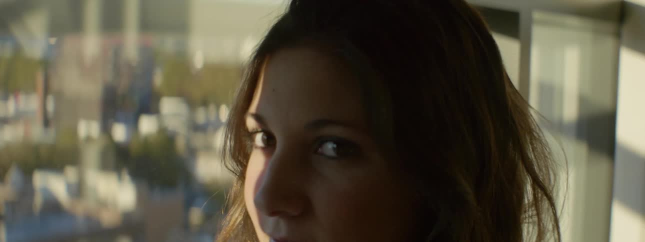 A woman smiles and turns to look out a window