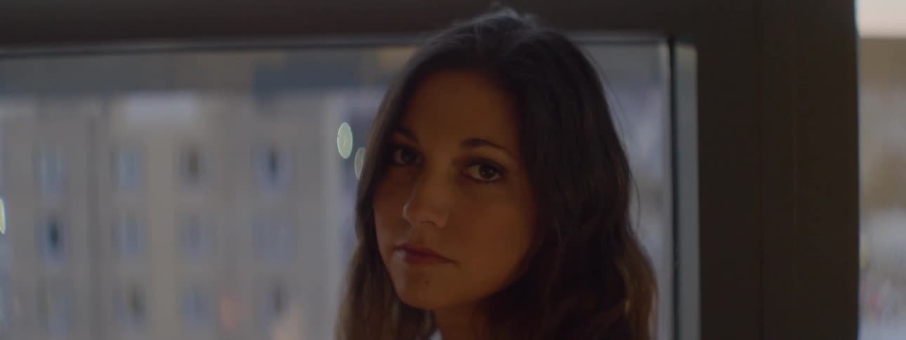 A dark haired woman turns from a window