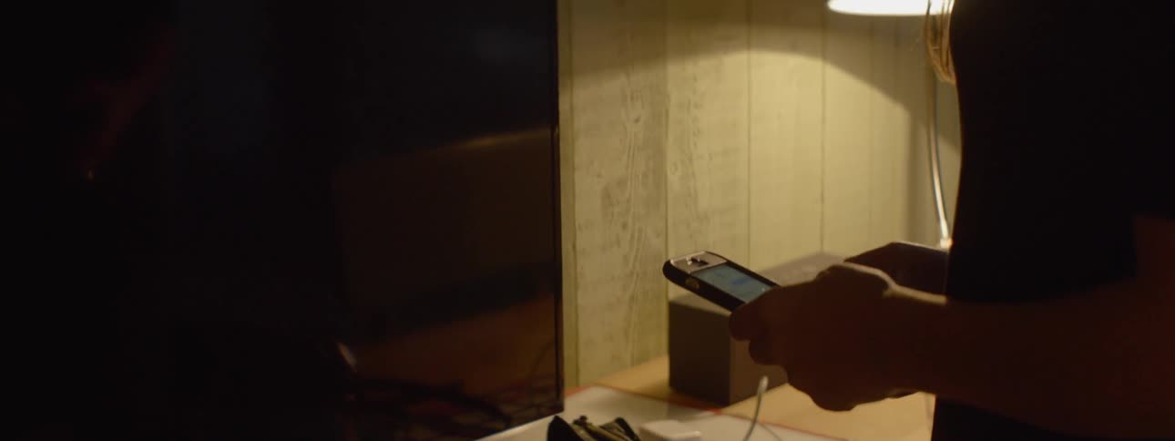 Woman in house picks up and scrolls through a cell phone
