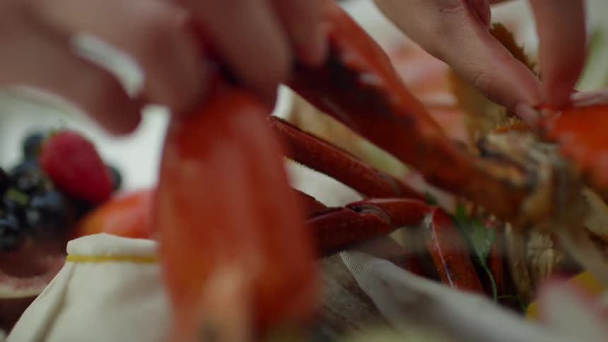 A man picks up a lobster claw from a container of cooked lobster