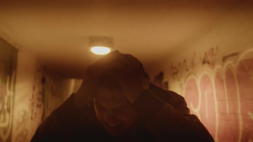 A man is holding his head screaming as a light flashes