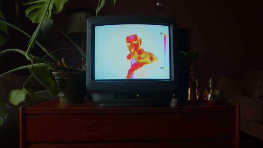 A room with a television set with a couch a wall and a lamp in the background