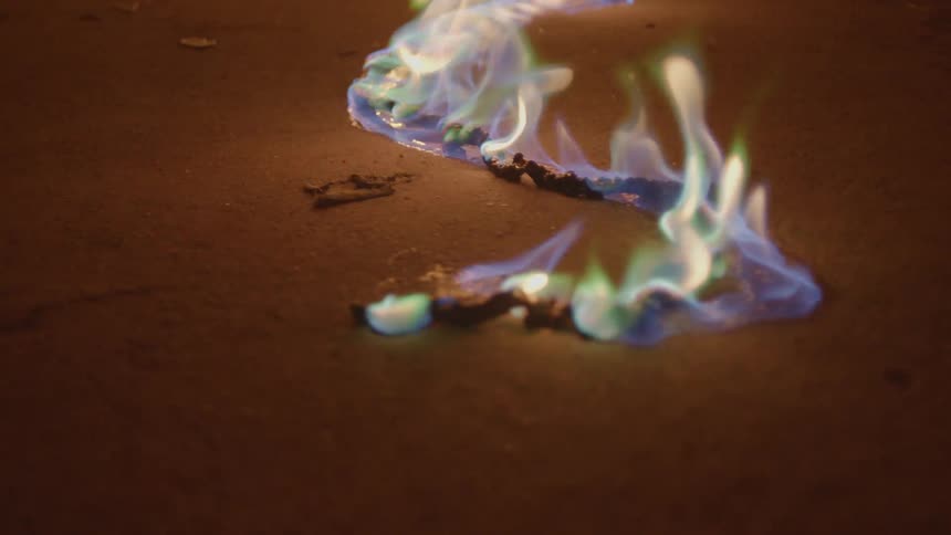 Colorful flames burn across cord on brown surface
