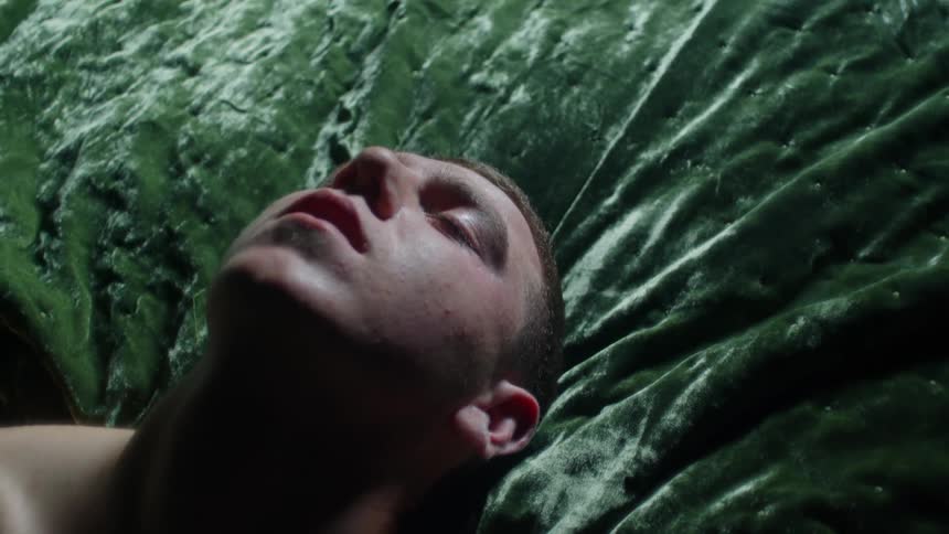 Man lies back against green velveteen cover sleeping