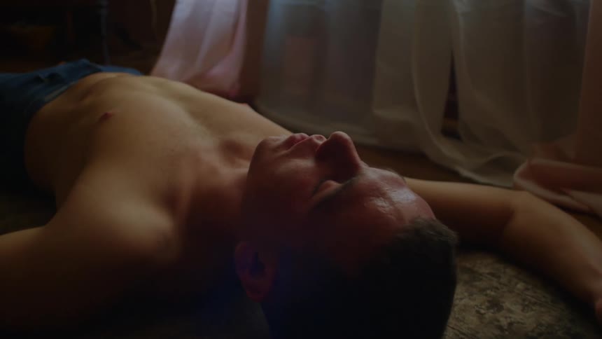 A teenage boy lies on the floor with his head rolling back and forth as his body shakes