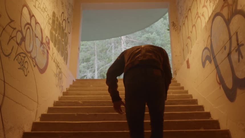 A man stumbles up the stairs heading outside