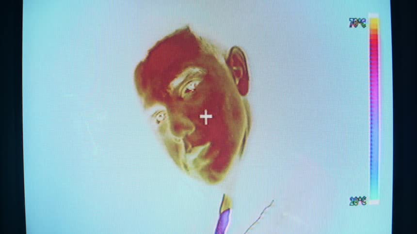 Thermal imaging of the face of a young man on a television screen