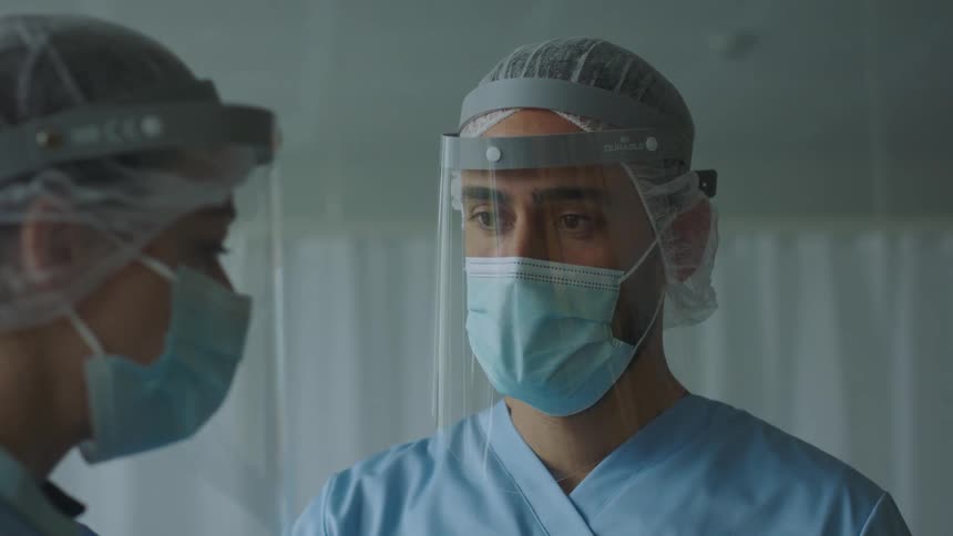 A man and a woman with a face shield and mask in a hospital room