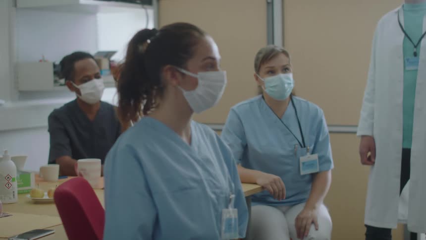 Hospital staff sit together listeningand nodding