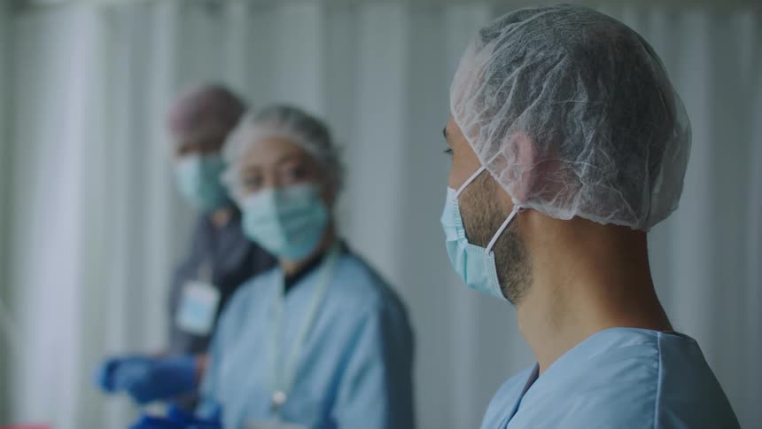 Nurses and doctors wearing face masks talking to each other in a hospital room