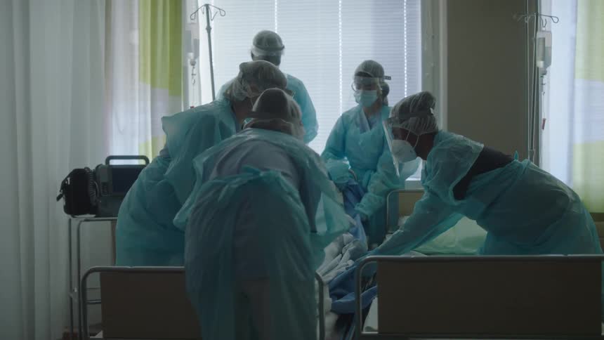 Group of doctors and nurses moving a patient from one bed to another in a hospital