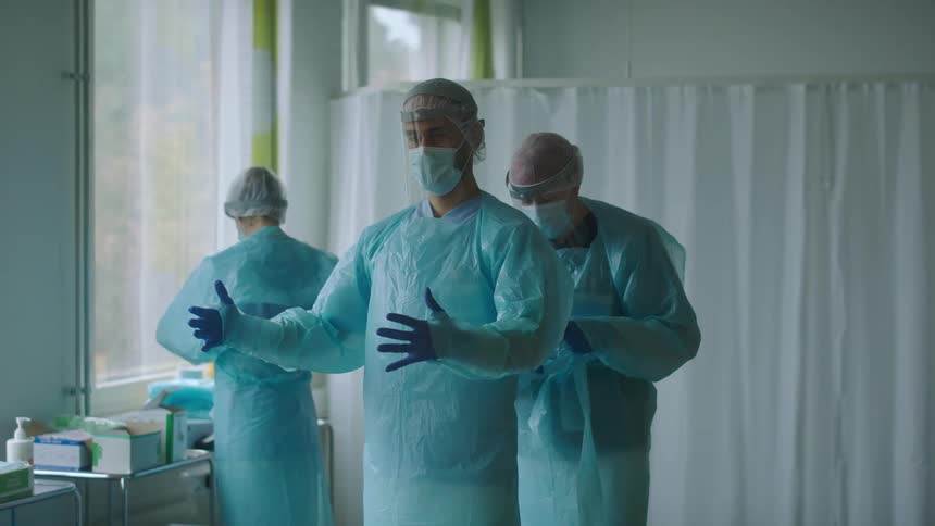 Nurses and doctors dressing with protective gear on a hospital room