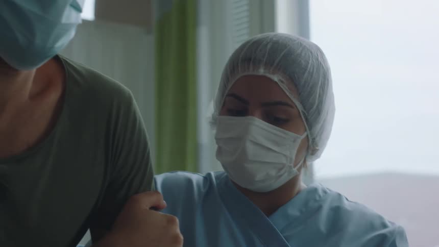 Nurses helping a patient to stand up from bed on a hospital room