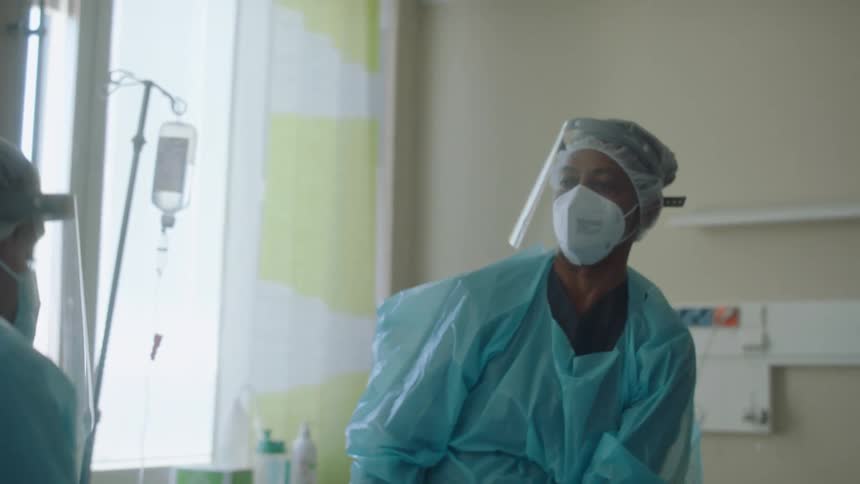 Hospital personnel consult in hospital room before moving patient to hospital bed