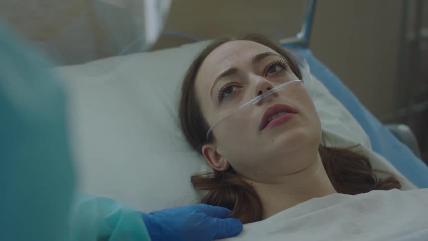 Doctor calming down a nervous patient laying in bed with a nasal cannula