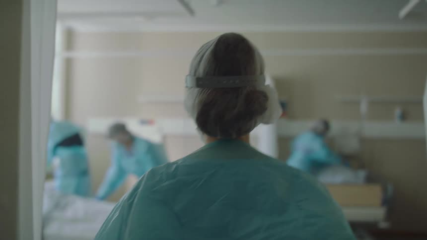 Doctor walks through a supply closet to enter a hospital room
