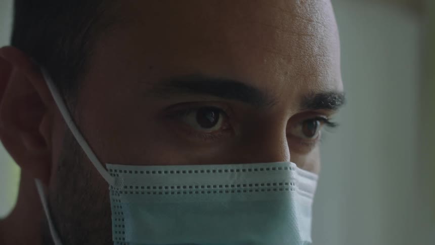 Close up of mans face with beard and light blue mask