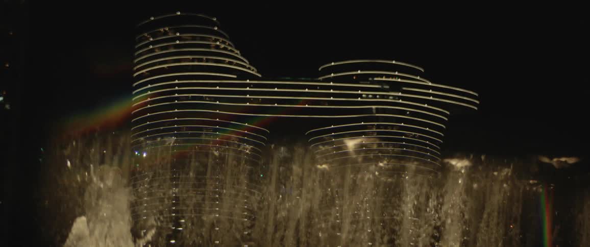An elaborate water fountain moves streams of water up and down in front of a downtown building