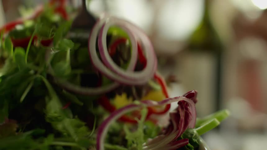 A person mixing salad on a bowl over a table