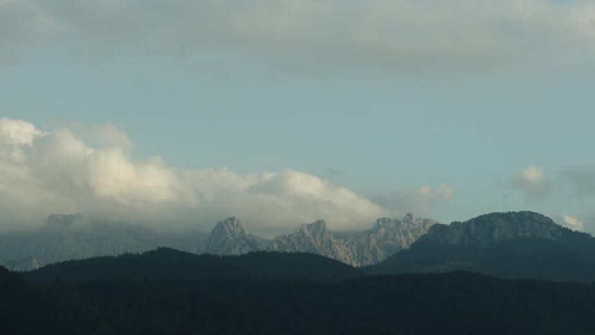 A landscape with a mountain range with the sky and clouds in the background