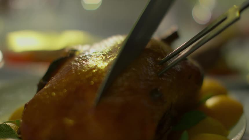 A piece of meat on a table being cut with a knife