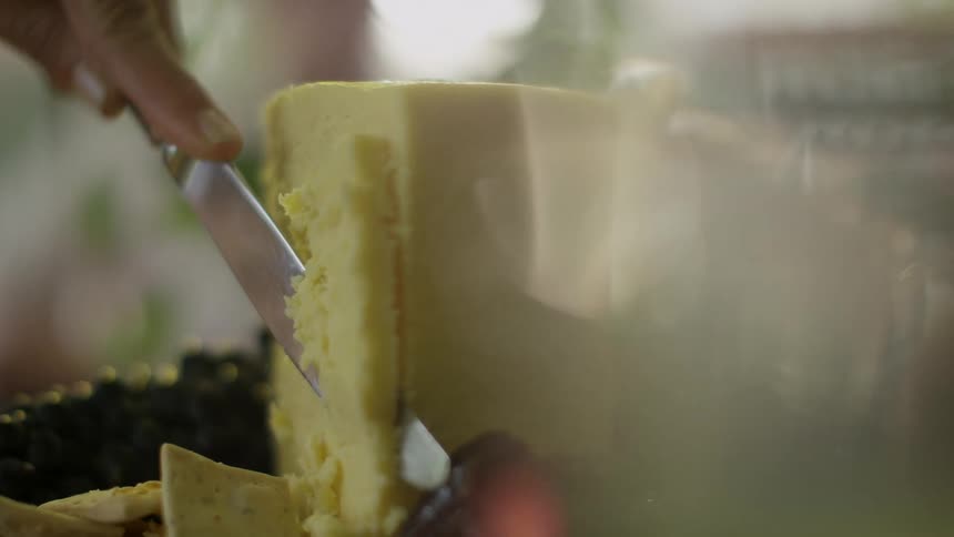 A person cutting cheese with a knife