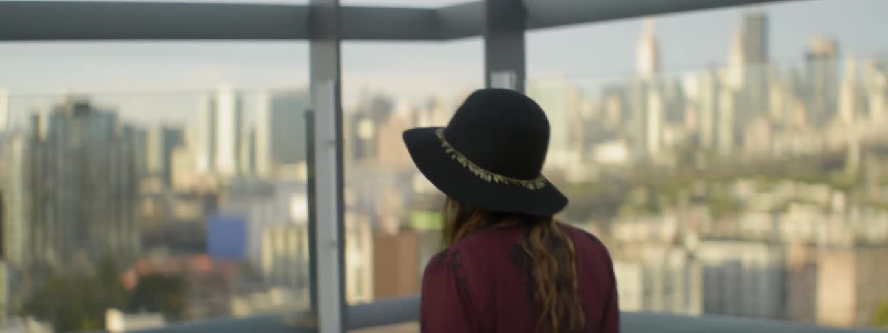 Woman in hat looking at a large city through a window