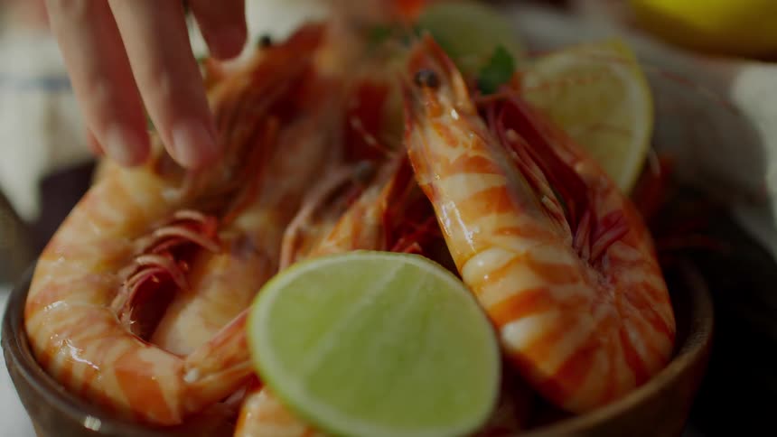 A person grabbing shrimp out of a bowl