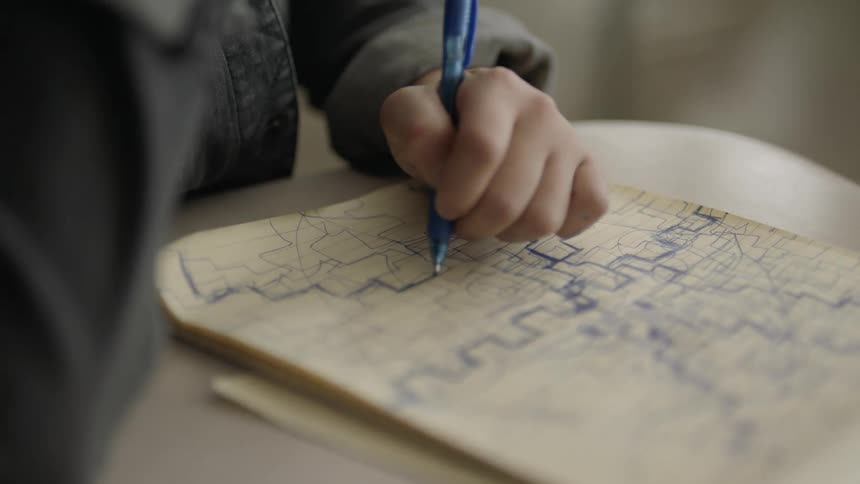 A young person is drawing on paper with a pen