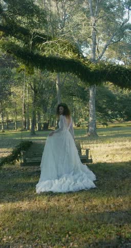A woman is standing outside wearing a wedding dress and looking around