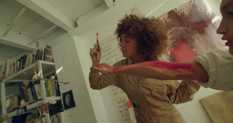 Woman painting the arm of a teenager pink and red with a brush