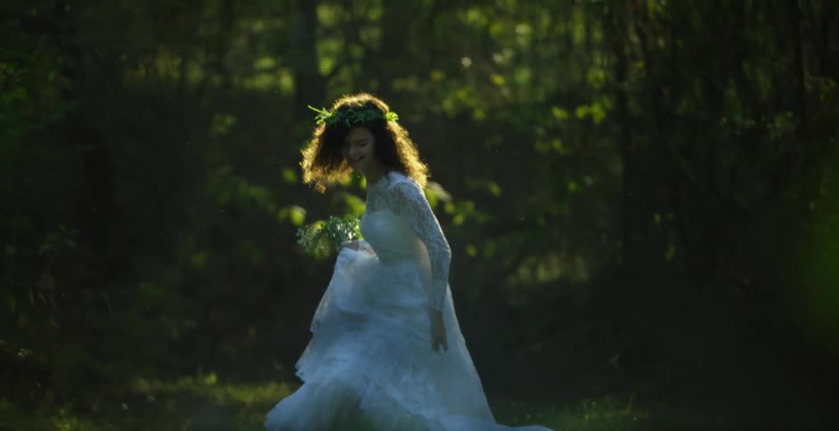A woman in a lace wedding gown holding a bouquet spins and laughs as she poses