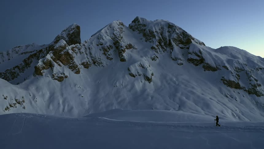 A wide shot of a mountain with a person walking towards it